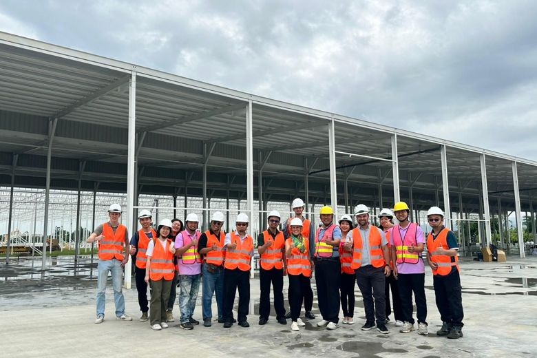 Gruppe mit Personen auf einer Baustelle, die orangefarbene Sicherheitswesten tragen